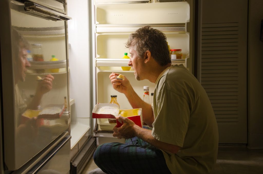 man eating straight out of the fridge