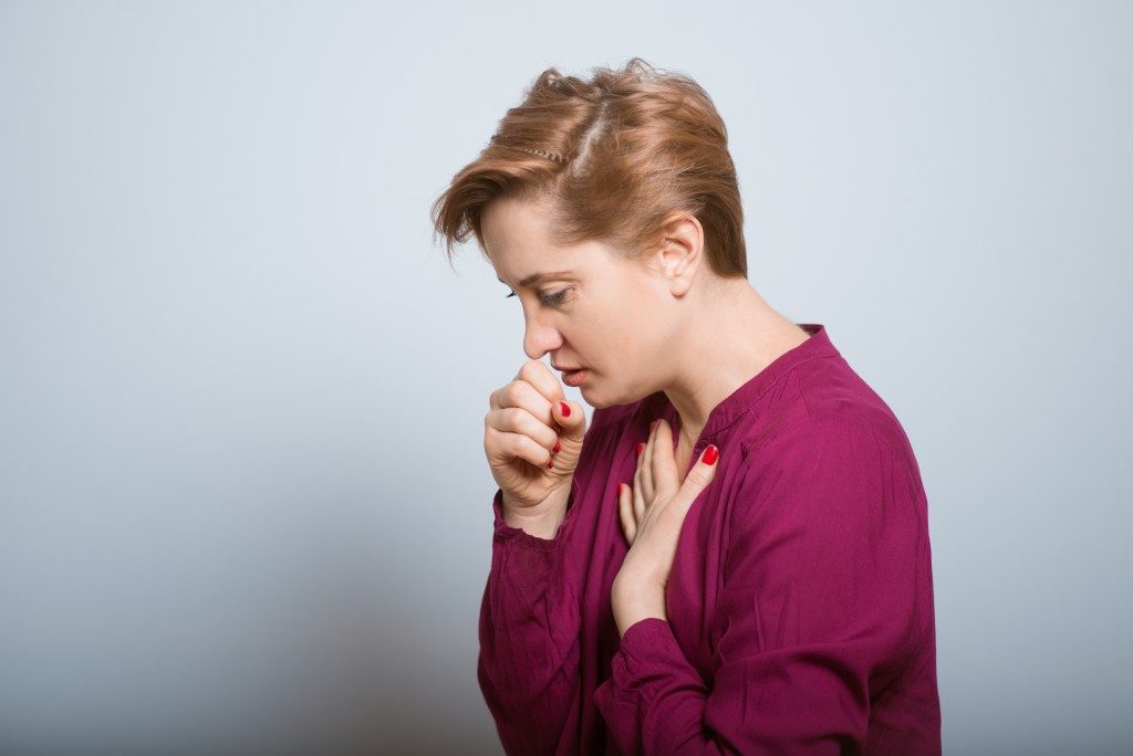 Woman coughing holding her chest