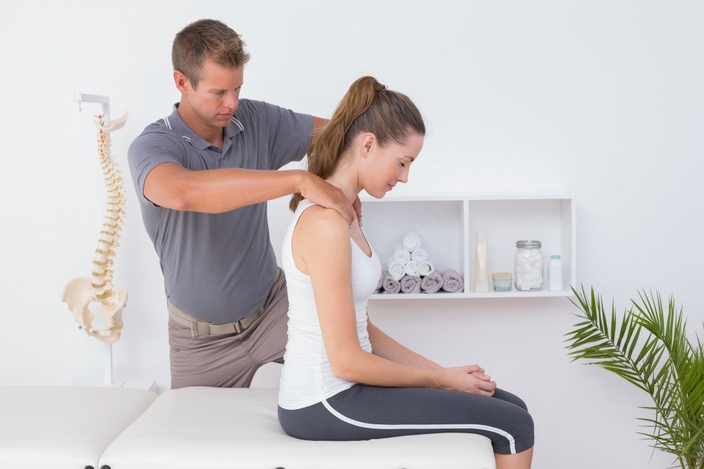 CHiropractor checking woman's back while inside the clinic