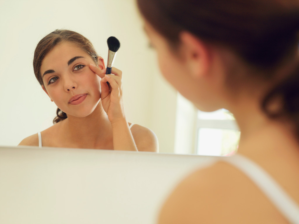 woman in front of mirror using makeup