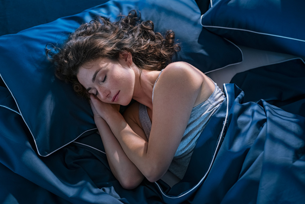 curly woman sleeping in a blue satin bed
