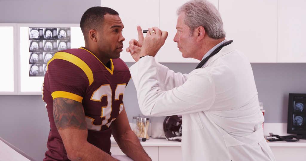 male doctor checking male athlete's eyes for concussion