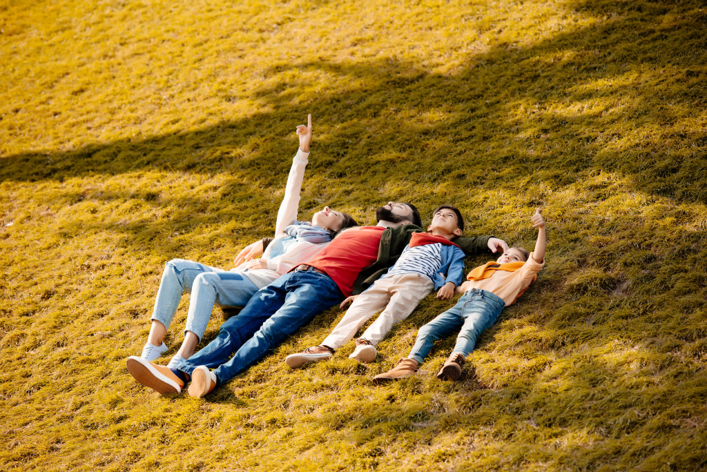 A family lying on the grass and looking at clouds